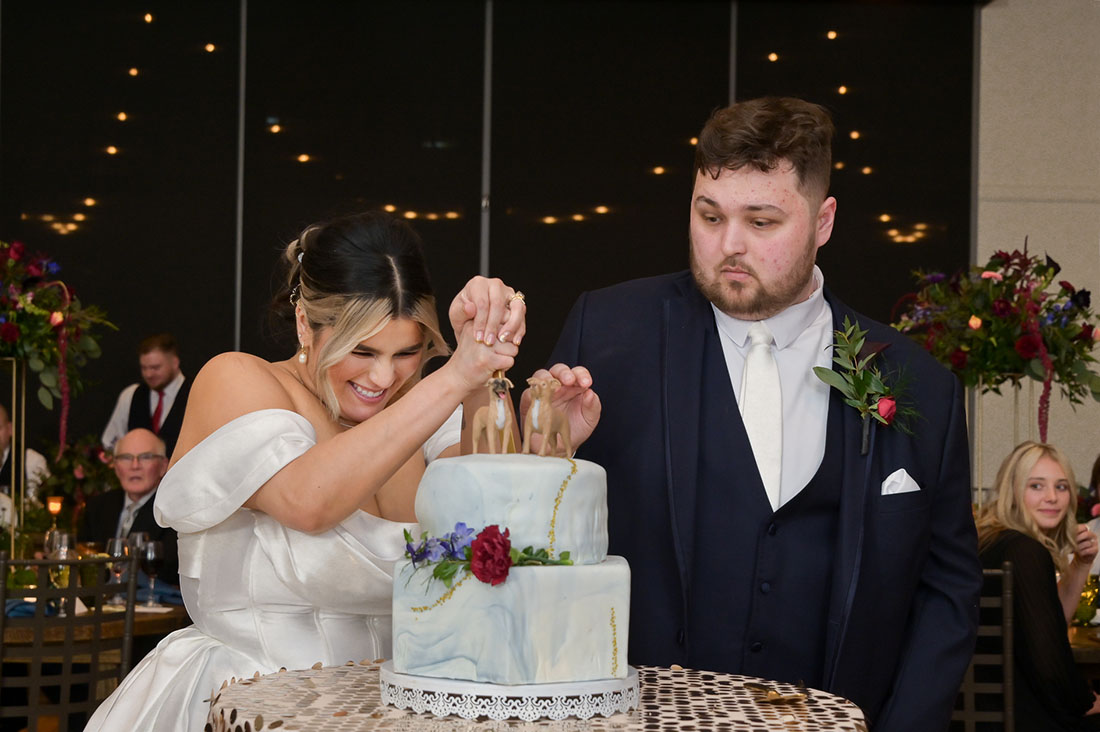 The bride and groom attempt to stab their cake, not realizing there was a fake layer at 2GatherMore, a wedding venue in Auburn Hills, Michigan.