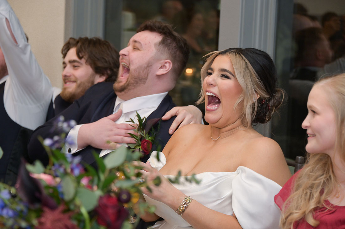 The bride and groom laugh like crazy during speeches at their wedding at 2GatherMore, a wedding venue in Auburn Hills, Michigan.