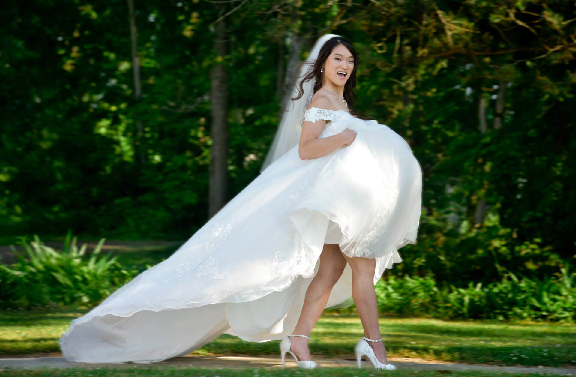 The bride hikes up her wedding dress as she heads out on a hot wedding day at Waldenwoods Resort in Howell, Michigan.