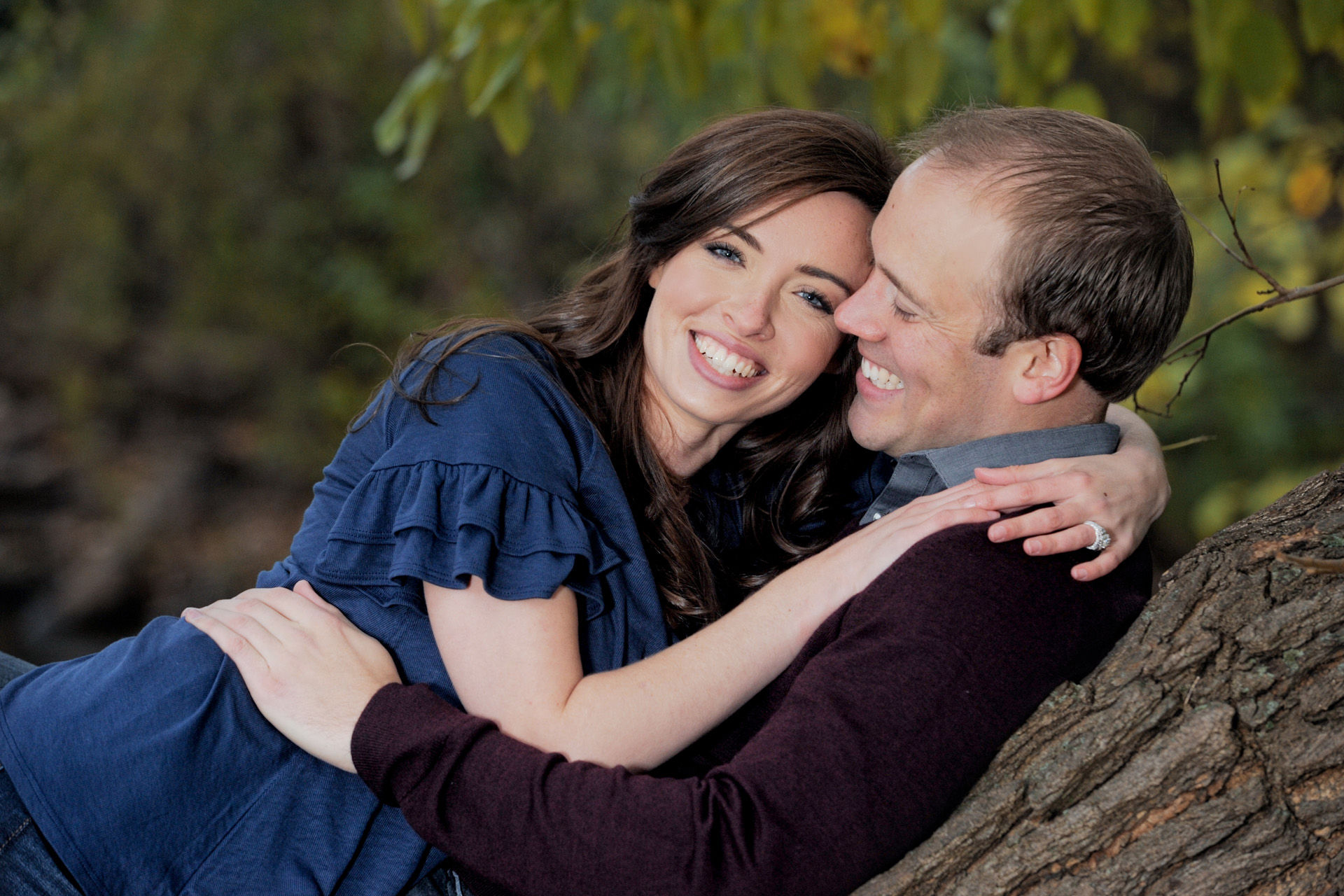 Engagement photos of a metro Detroit engaged couple snuggling in a tree in the Metro Detroit, Michigan parks.