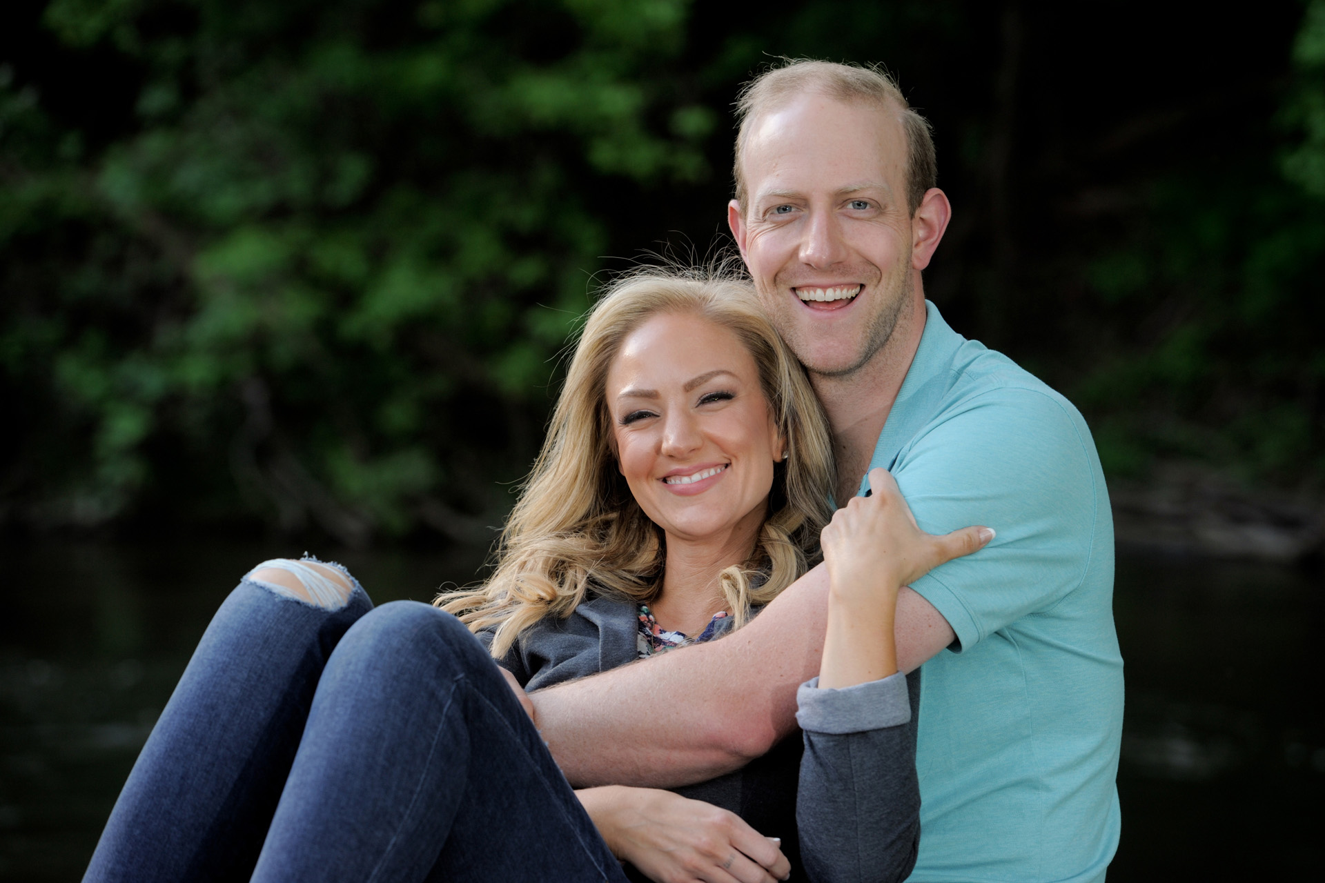 A couple snuggling at a park in metro Detroit, Michigan for their engagement session.