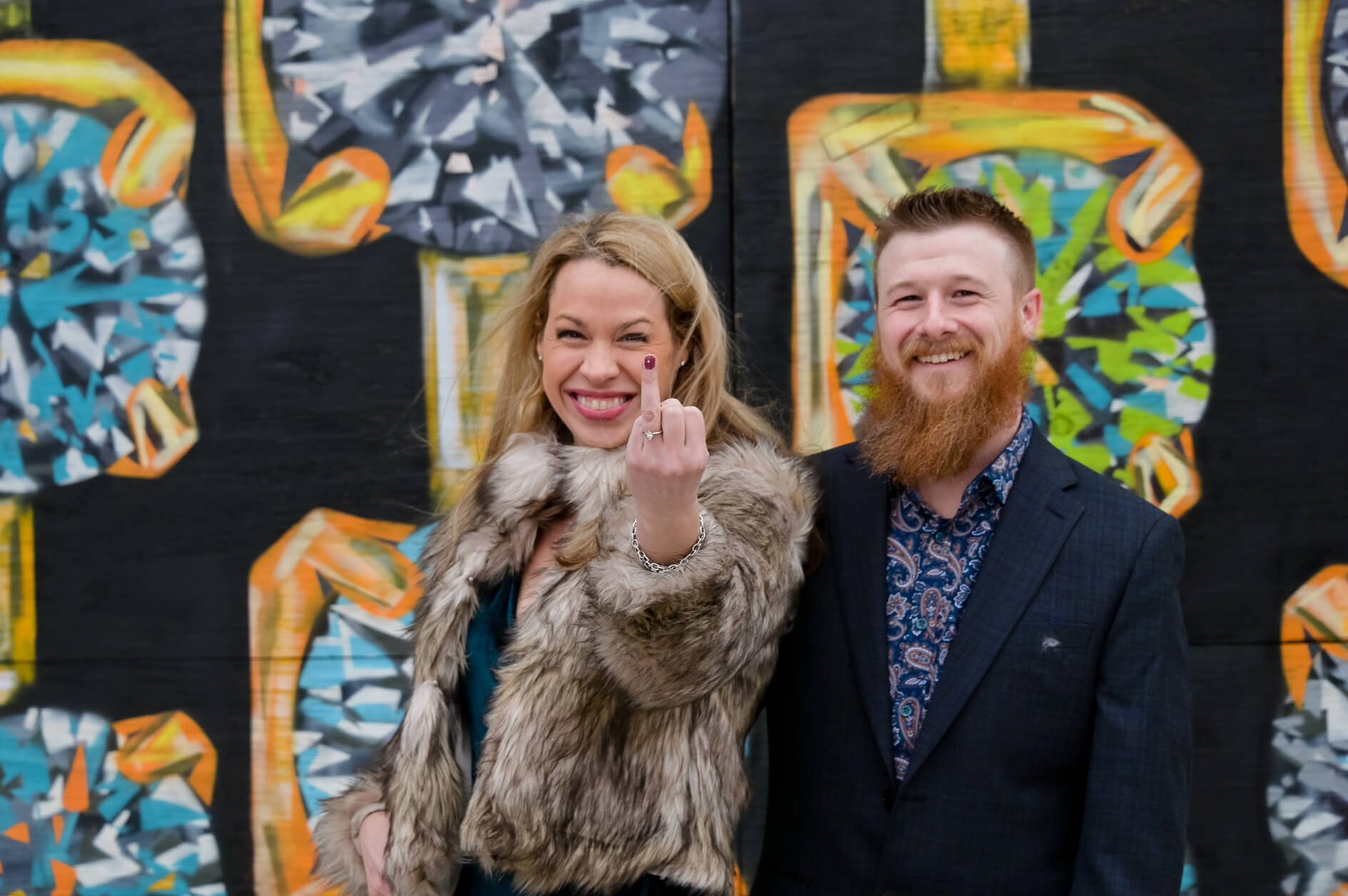 Playful photo of a bride giving me the finger (with a nice ring on it) for engagement photos of a Michigan newly engaged couple with ever changing graffiti art in Detroit's Eastern Market.