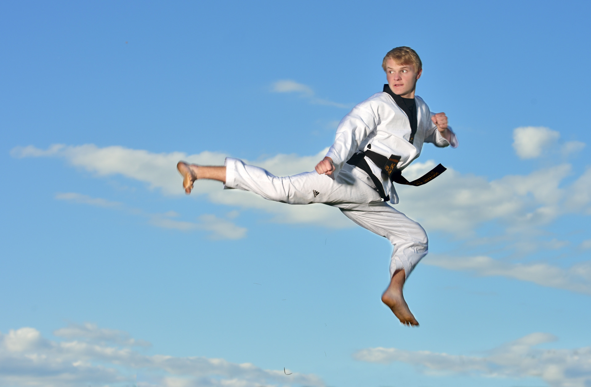 Troy High School student shows off his taekwondo skills on a hilltop in Birmingham, Michigan for a dynamic, powerful senior photo.