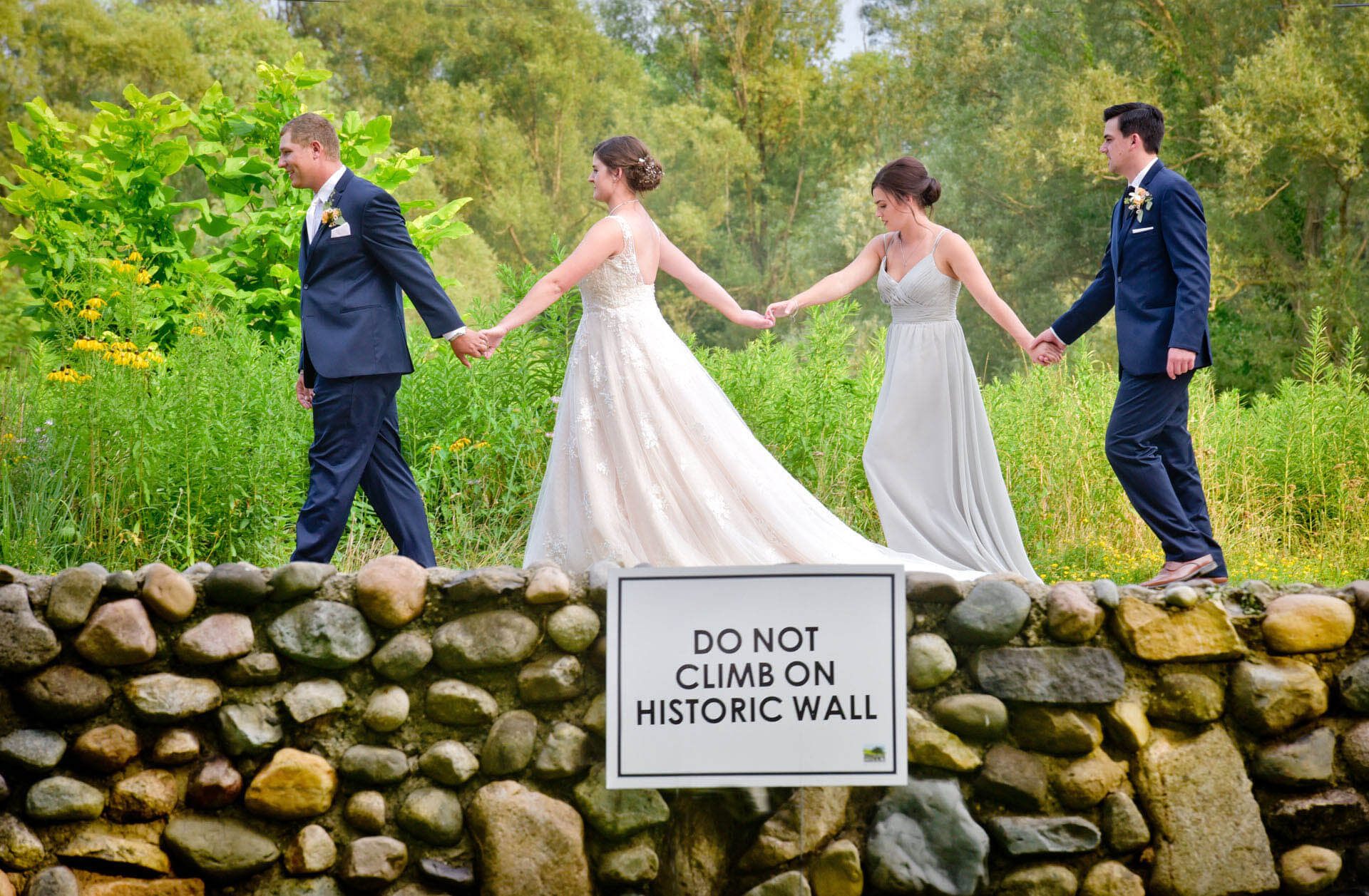 The bridal party walks along the road for a sight gag at Van Hoosen Museum during a wedding in Rochester, Michigan.