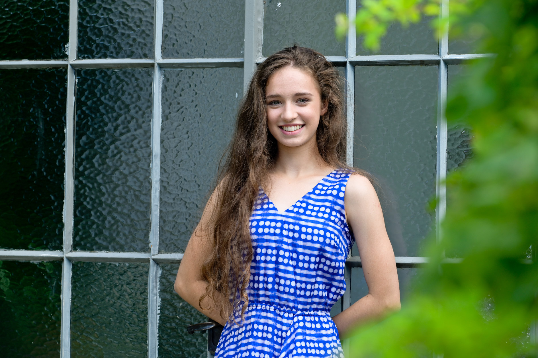 Leaning against a glass wall of an art studio at Cranbrook Kingswood High School in Bloomfield Hills, Michigan for fun high school senior pictures.