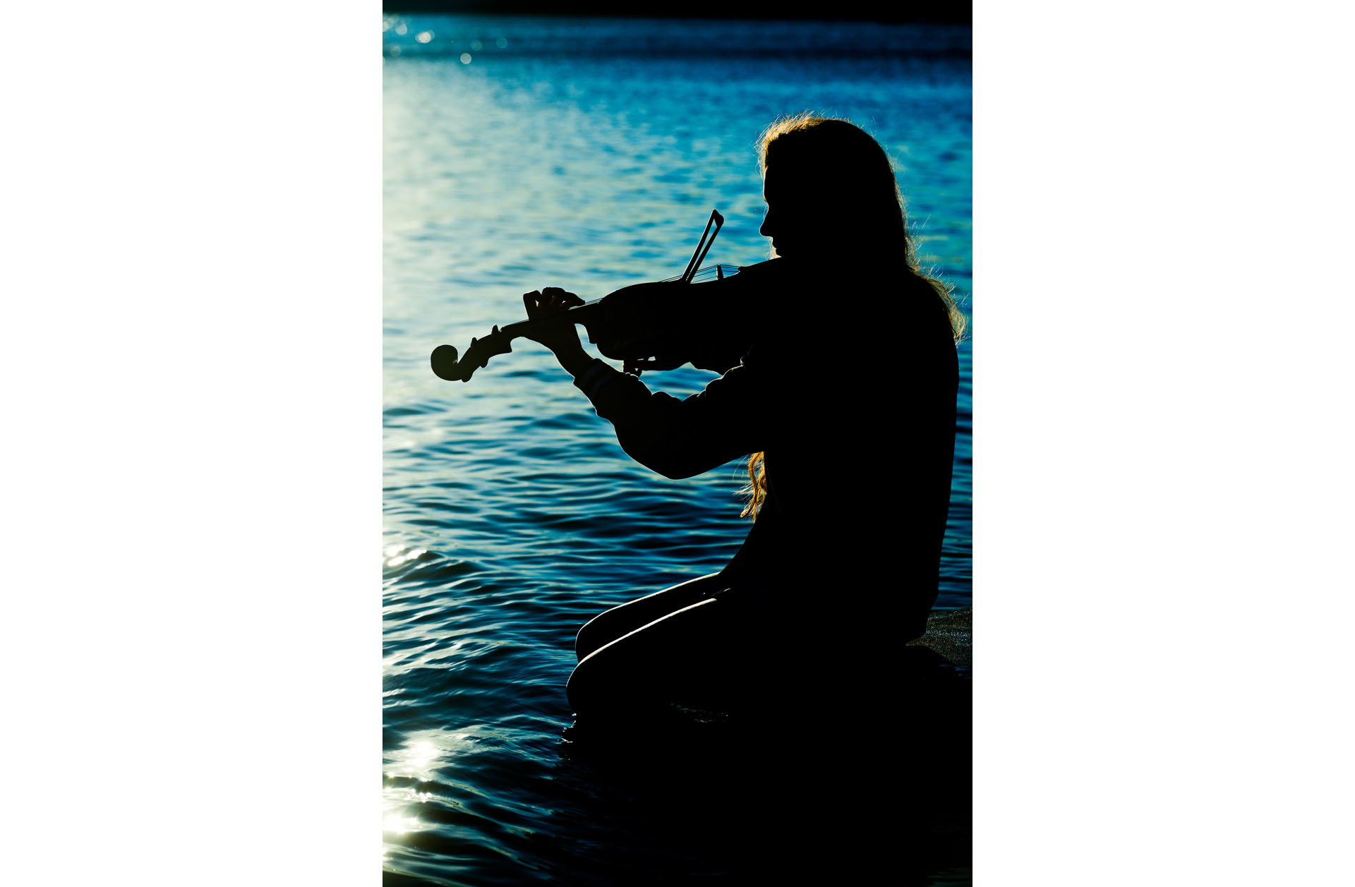 Rachel ended her artistic series of senior photos from Cranbrook Kingswood High School in Bloomfield Hills silhouetted as the sun goes down on the docks playing her violin.
