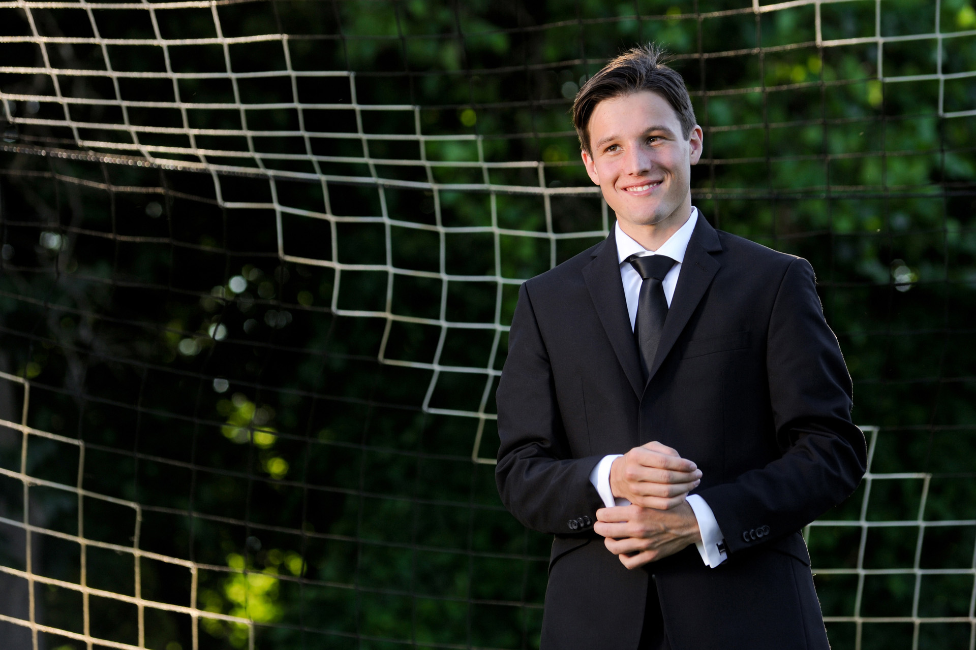 Cranbrook School in Bloomfield, Michigan senior photographer's photo of a high school senior posing with in the soccer goal for a James Bond type sports photo for his senior pictures at Cranbrook School in Bloomfield, Michigan.