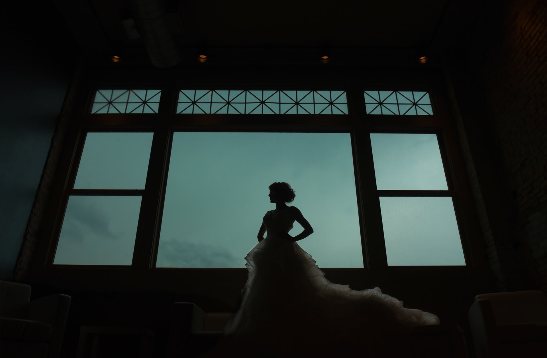 Epic wedding day bride portraits like this one taken at the Crofoot Ballroom in Pontiac, Michigan features a bride standing at the window just before a storm blew in.