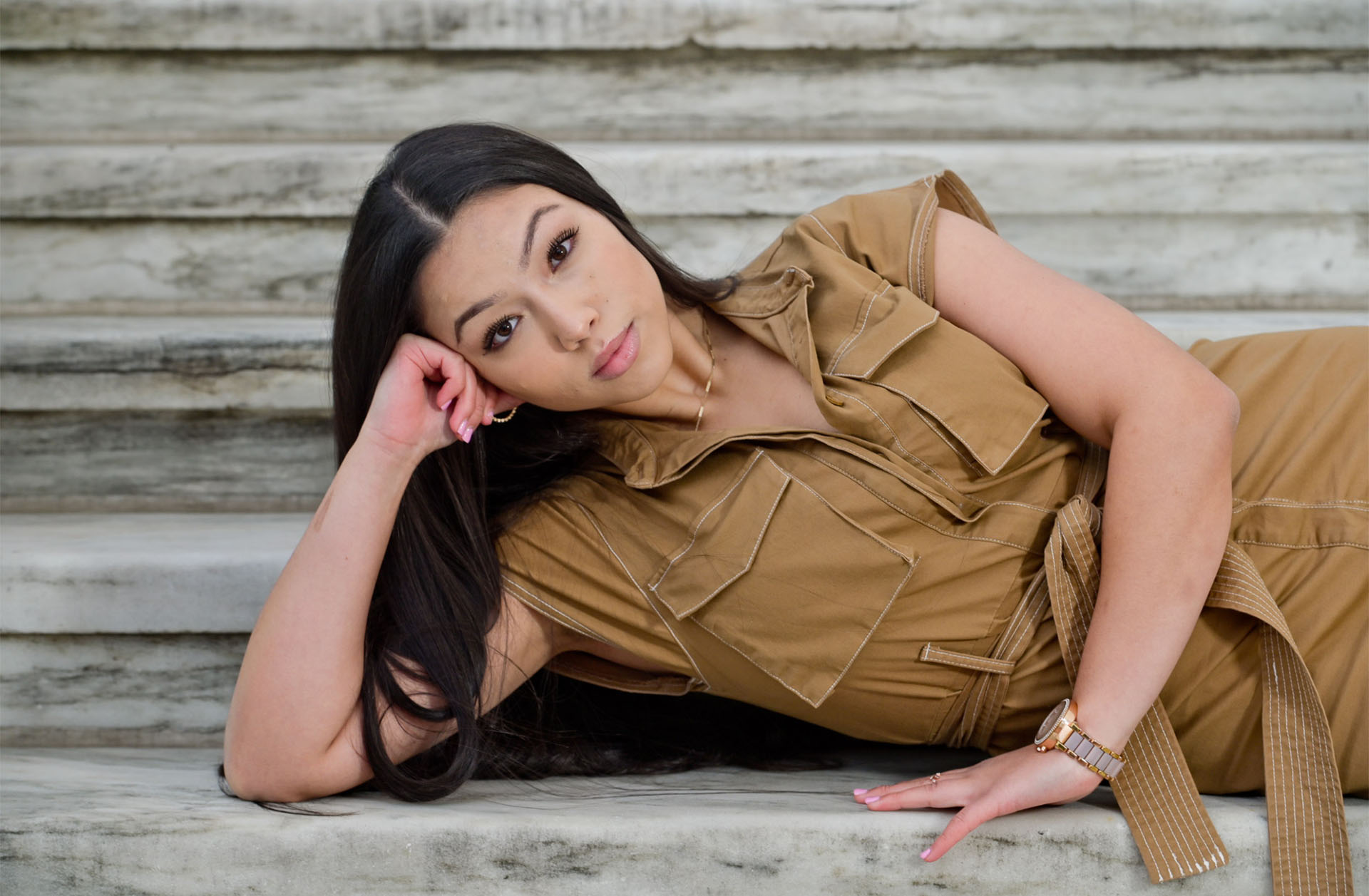 A high school senior girl laying on the steps at the Detroit Institute of Arts in Detroit, Michigan.