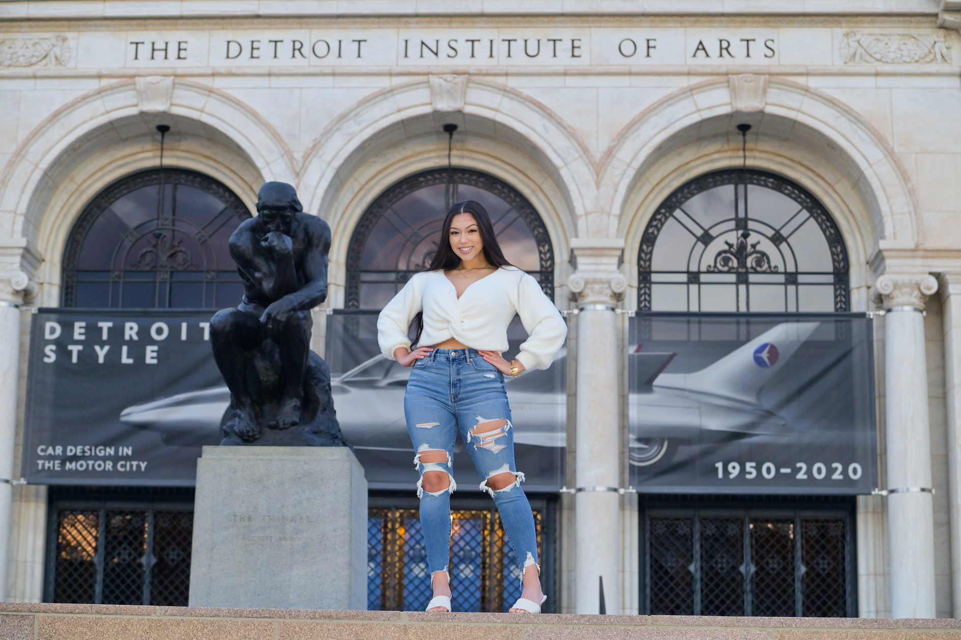 A high school senior girl stand on a ledge at the Detroit Institute of Arts in Detroit, Michigan.