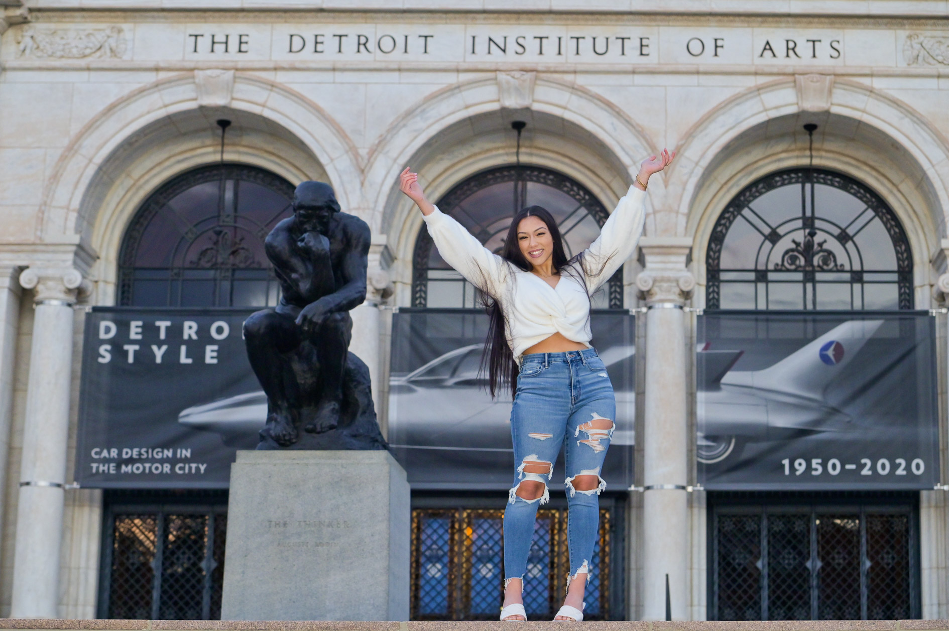 A high school senior girl posing in front of the Detroit Institute of Arts in Detroit, Michigan.