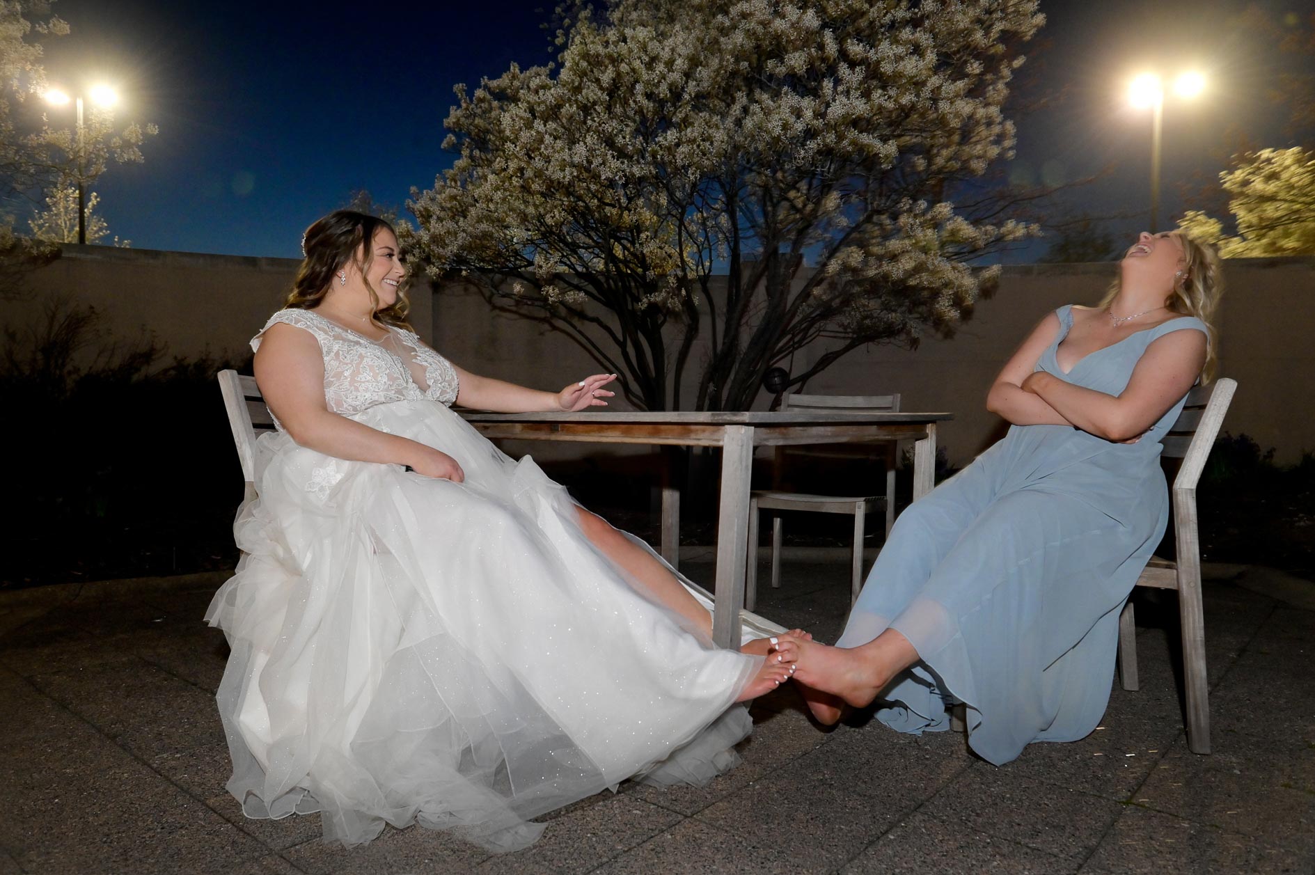 A bride plays footsie with her bridesmaid while taking a break from her wedding in Auburn Hills, Michigan.