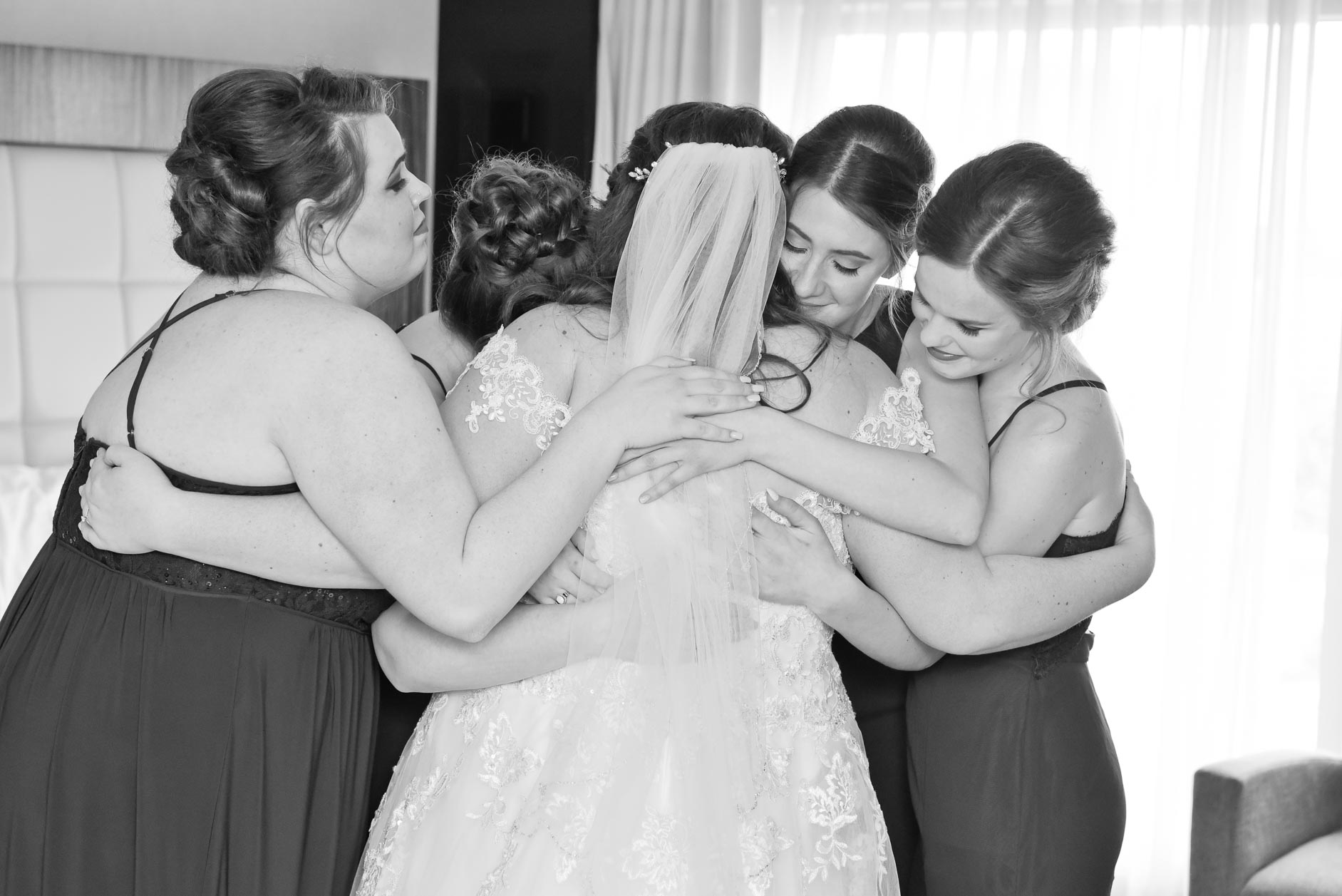 Bridesmaids all hug the bride after their first look at the Marriott Hotel at the Renaissance Hotel in Detroit, Michigan.
