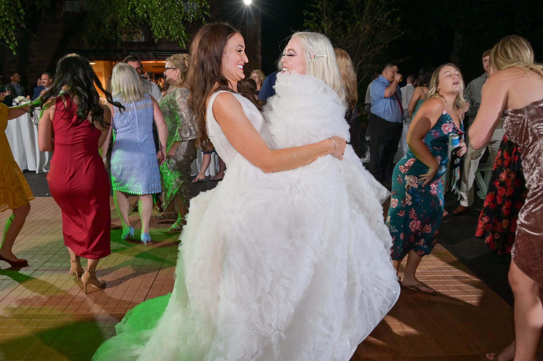 The bride wraps her bridesmaid up in her wedding dress on the dance floor at her Strawberry Lake Lodge wedding in Pinkney, Michigan.