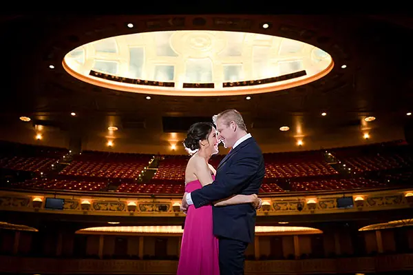 The bride and groom snuggle on the stage at the Detroit Opera House before their wedding in Detroit, MI.