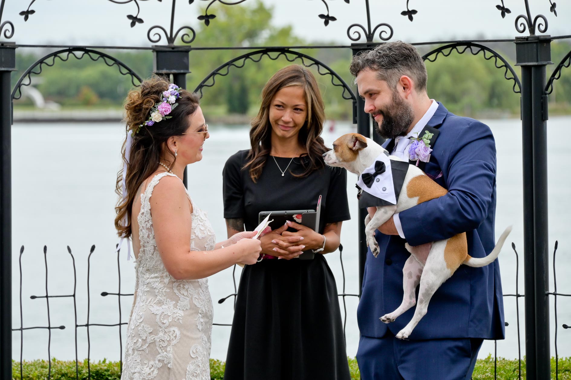 The bride and groom and their dog say their vows at the Roostertail wedding venue in Detroit, Michigan for a bit of lighthearted candid fun.