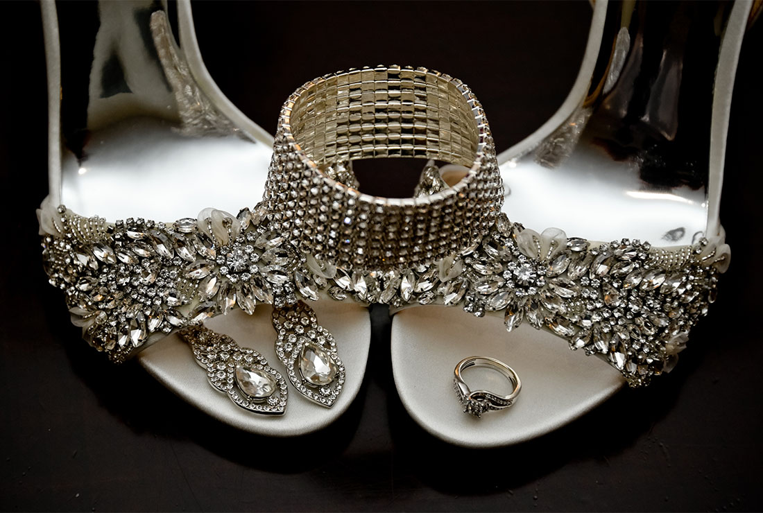 A Detroit bride's shoes and jewelry in this photo of her wedding details on a black table.