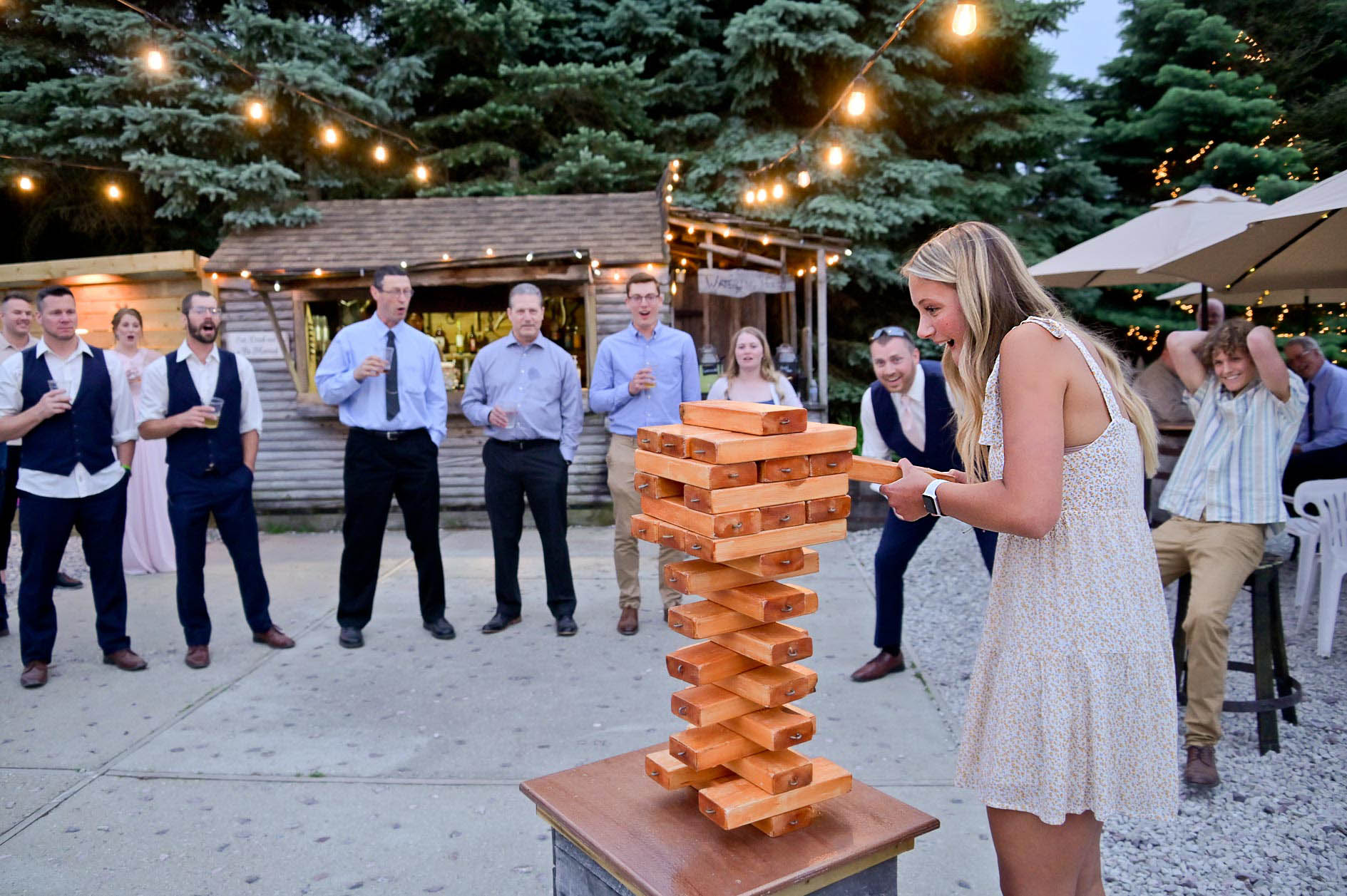 A wedding guest playing Giant Jenga while guests watch at the Christmas Tree Family Farm in Laingsburg, Michigan.