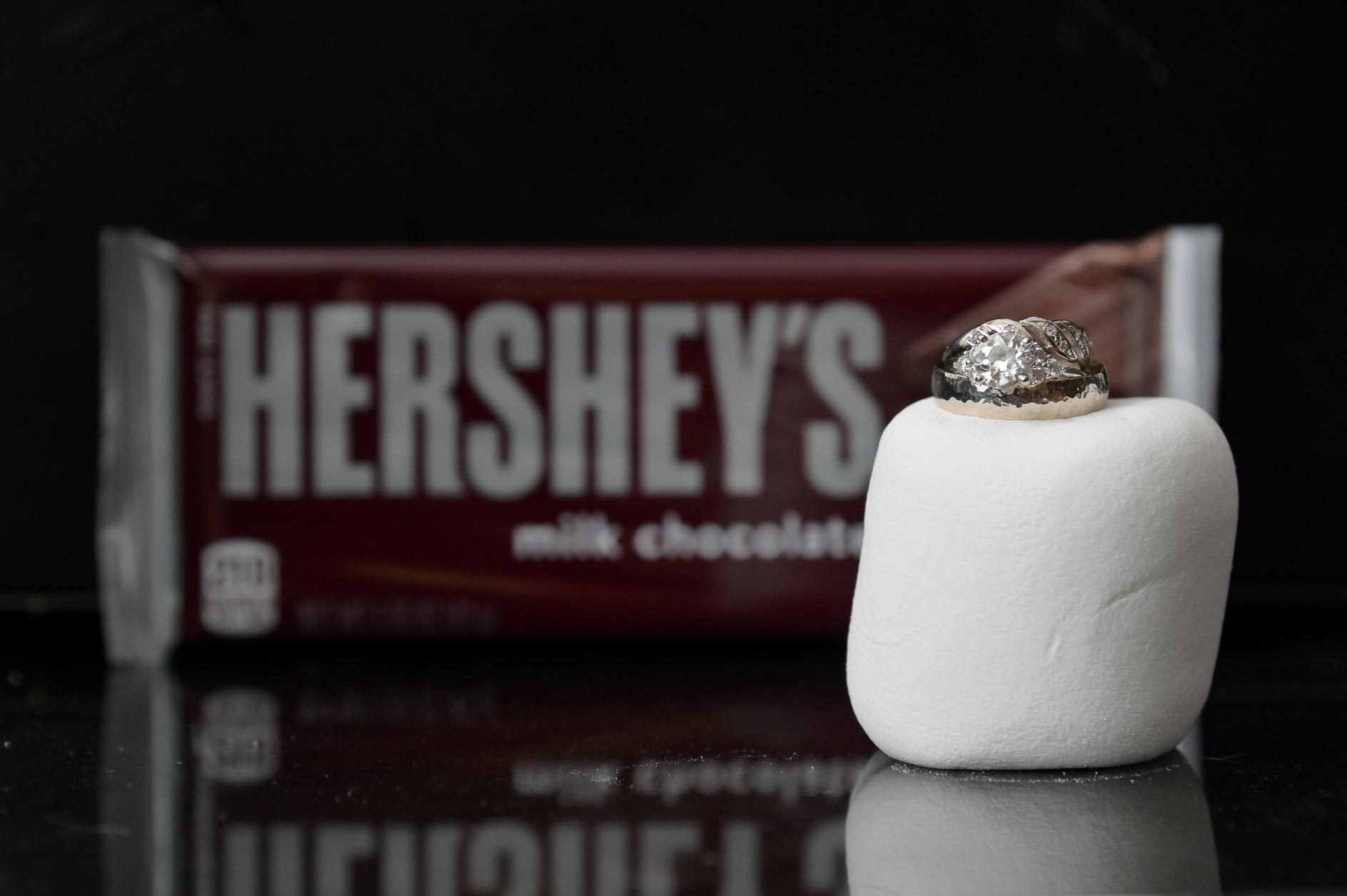 A wedding couple planning a bonfire and smores after their destination wedding in Vermont got their ring details photographed with a marshmallow and smores fixings.