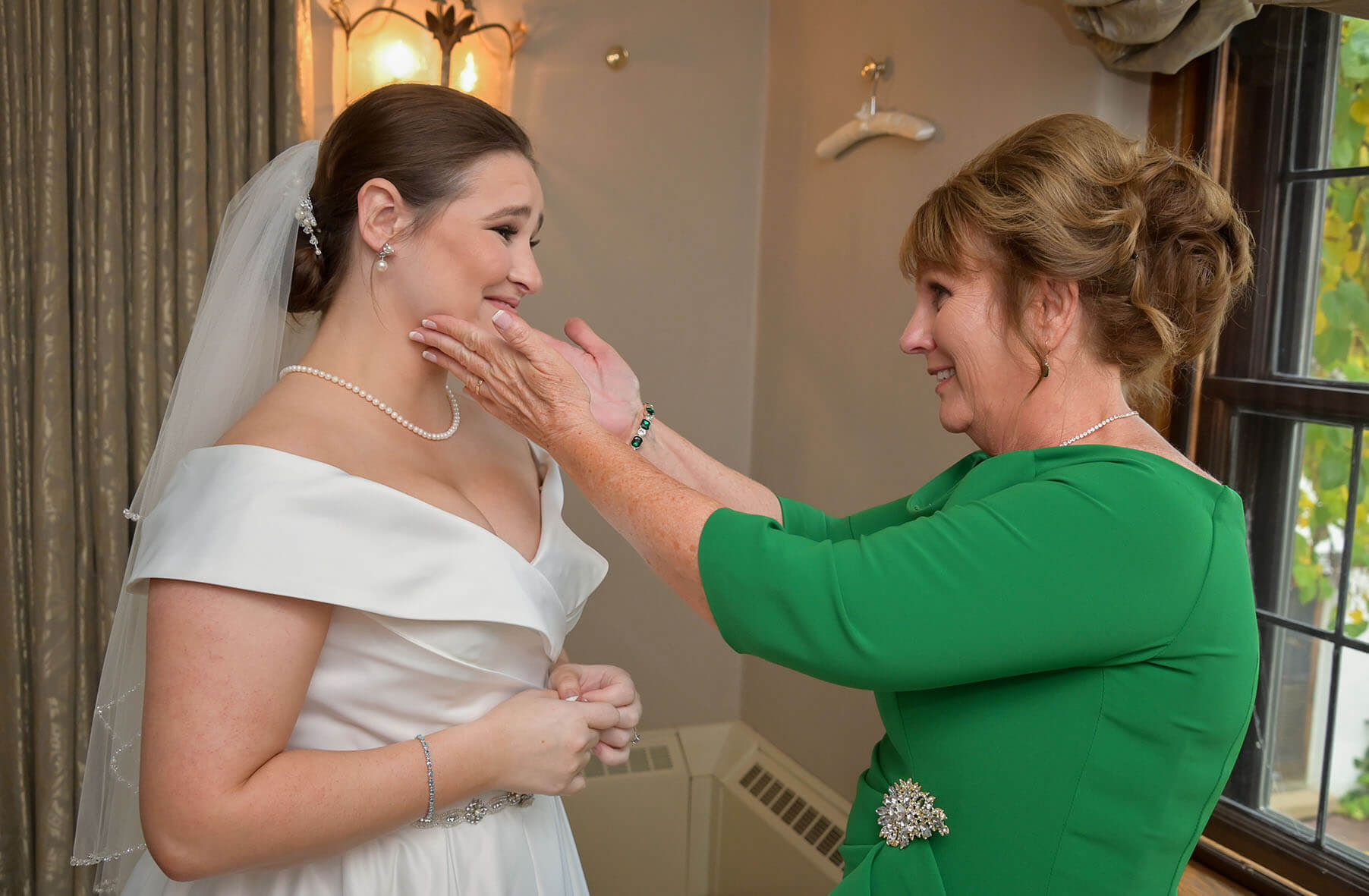 Wedding photo documenting a mother reaches for her daughter after seeing her daughter dressed for the first time for her wedding at Addison Oaks, Michigan.