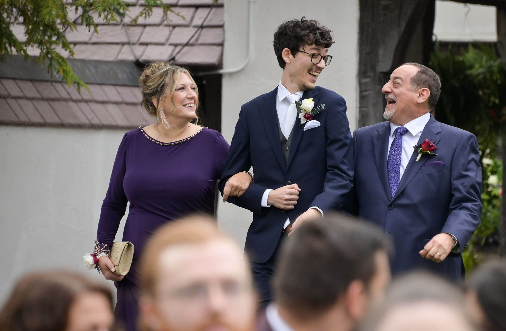 The groom walks down the aisle with his parents laughing at Addison Oaks Buhl Estate in Leonard Michigan.