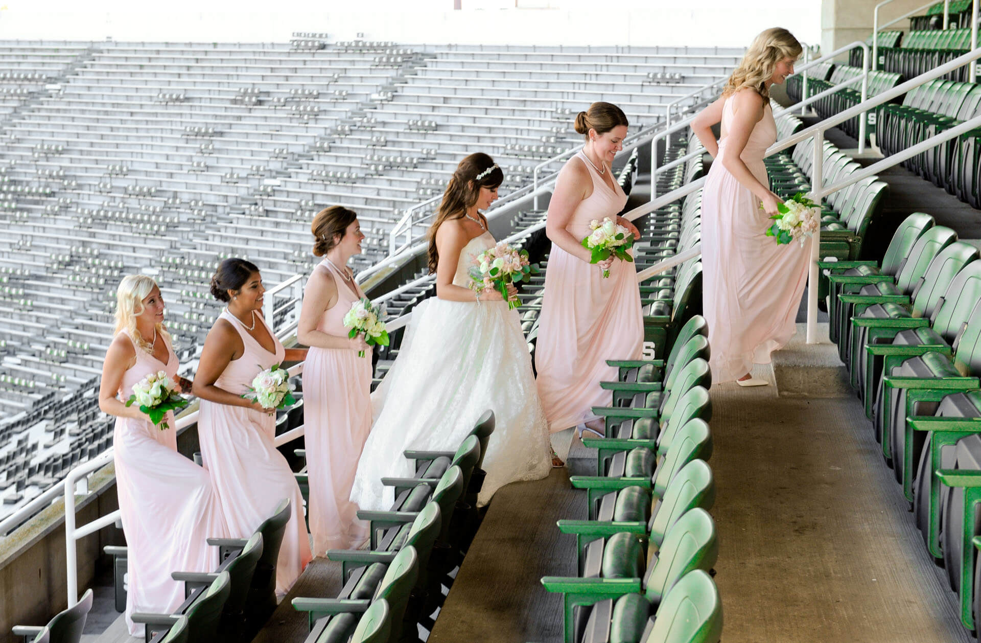 Epic Wedding portrait showing the bride and her bridesmaids heading back out of MSU's stadium during their wedding in East Lansing, Michigan.