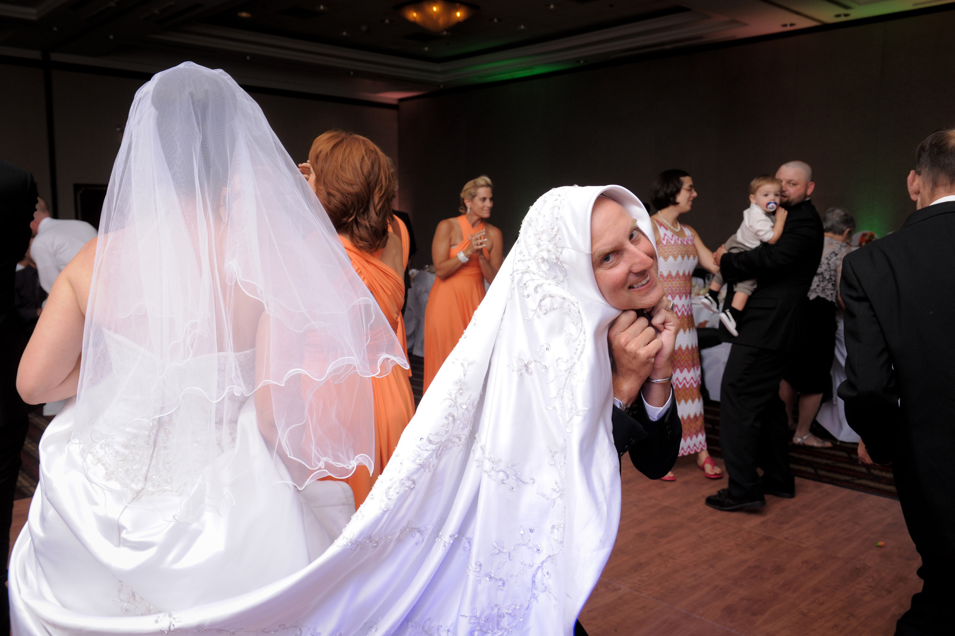 Michigan wedding at Sterling Heights, Michigan, Michigan wedding shows a photograph of the man on honor tending the bride's bustle during the wedding reception at the Wyndham Garden Hotel in Sterling Heights, Michigan (formerly known as the Sterling Inn) in Macomb County, Michigan.
