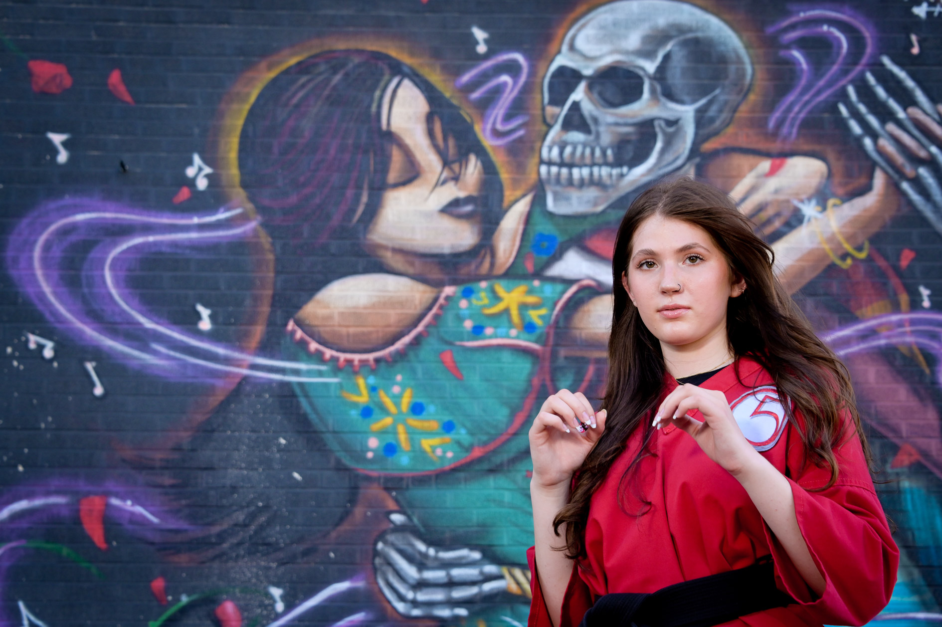 Fraser High school senior in her martial arts gear showing off a kick in front a wall mural in Detroit, Michigan.