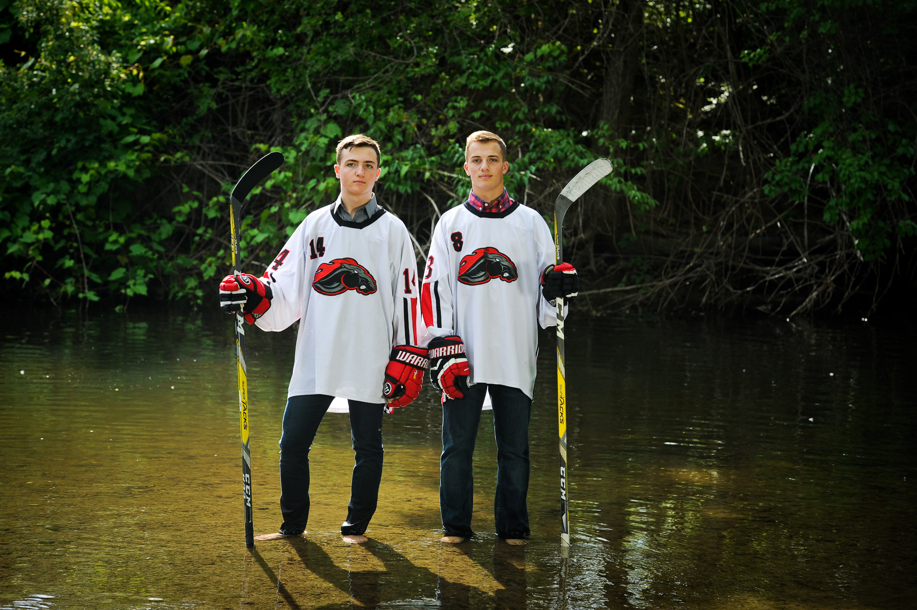 Troy Michigan high school twins pose with their hockey uniforms in the water near Rochester, Michigan.
