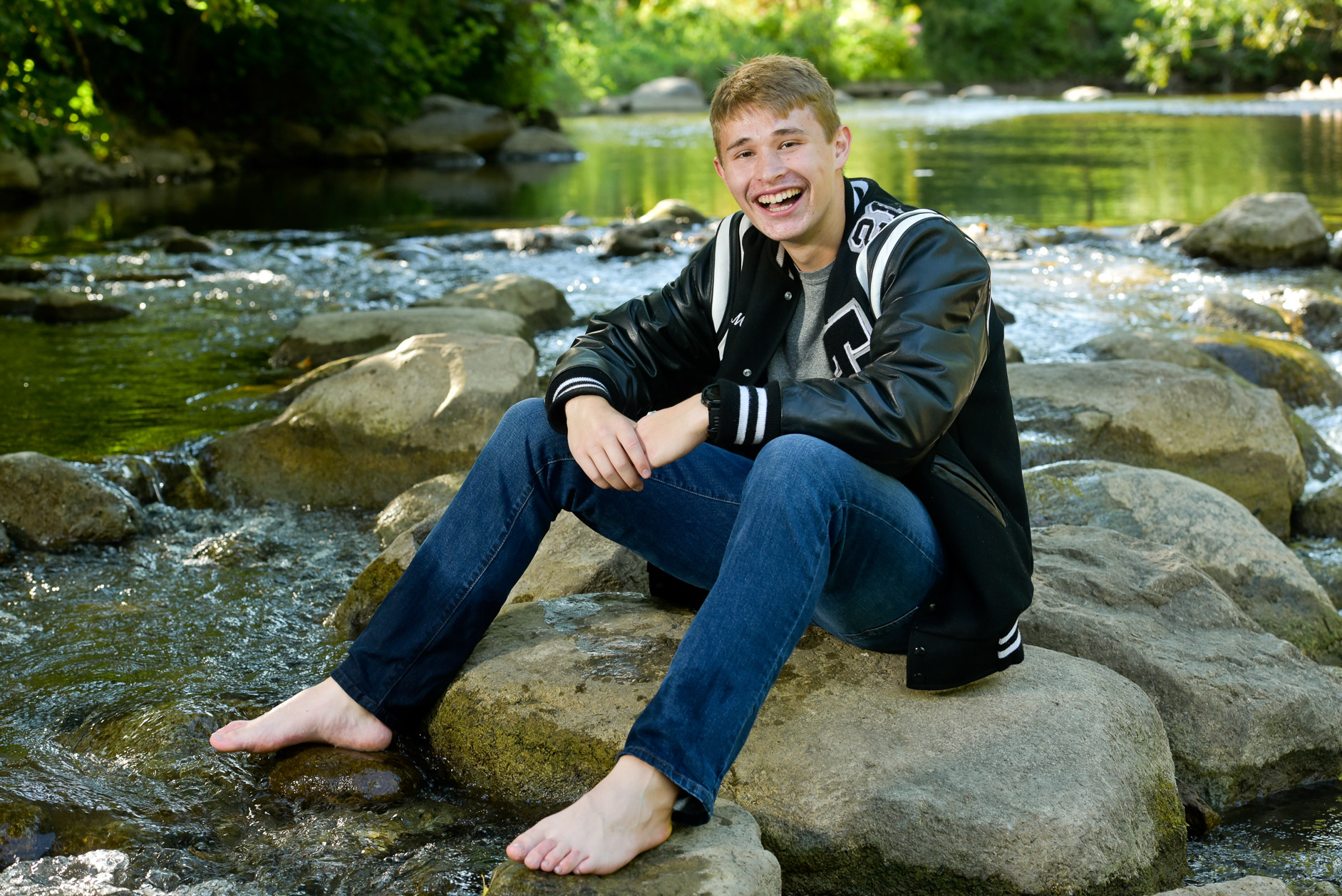 Troy High senior sits in the river with his letter jacket in Oakland County, Michigan.