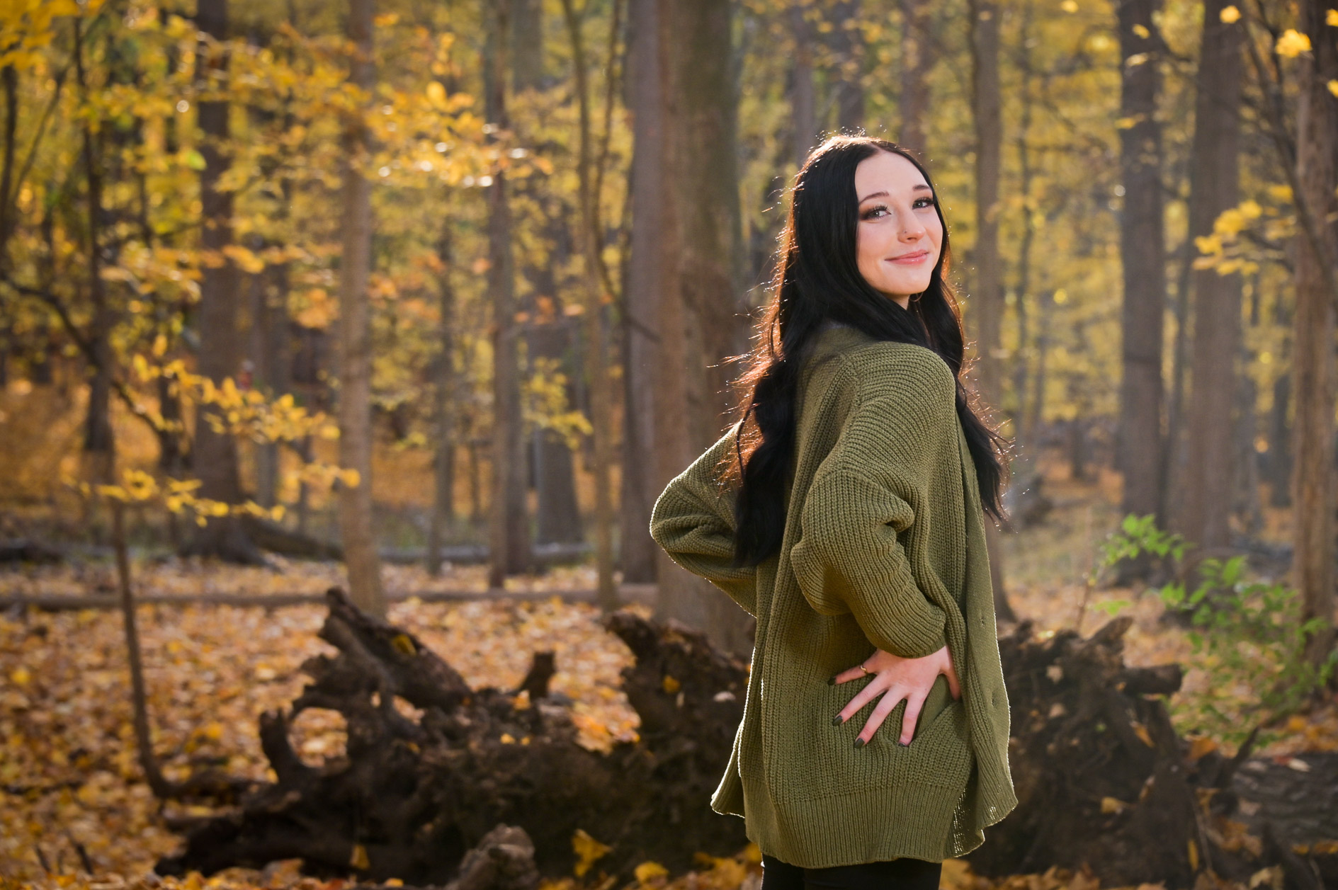 Senior girl having fun posing with orange fall leaves.