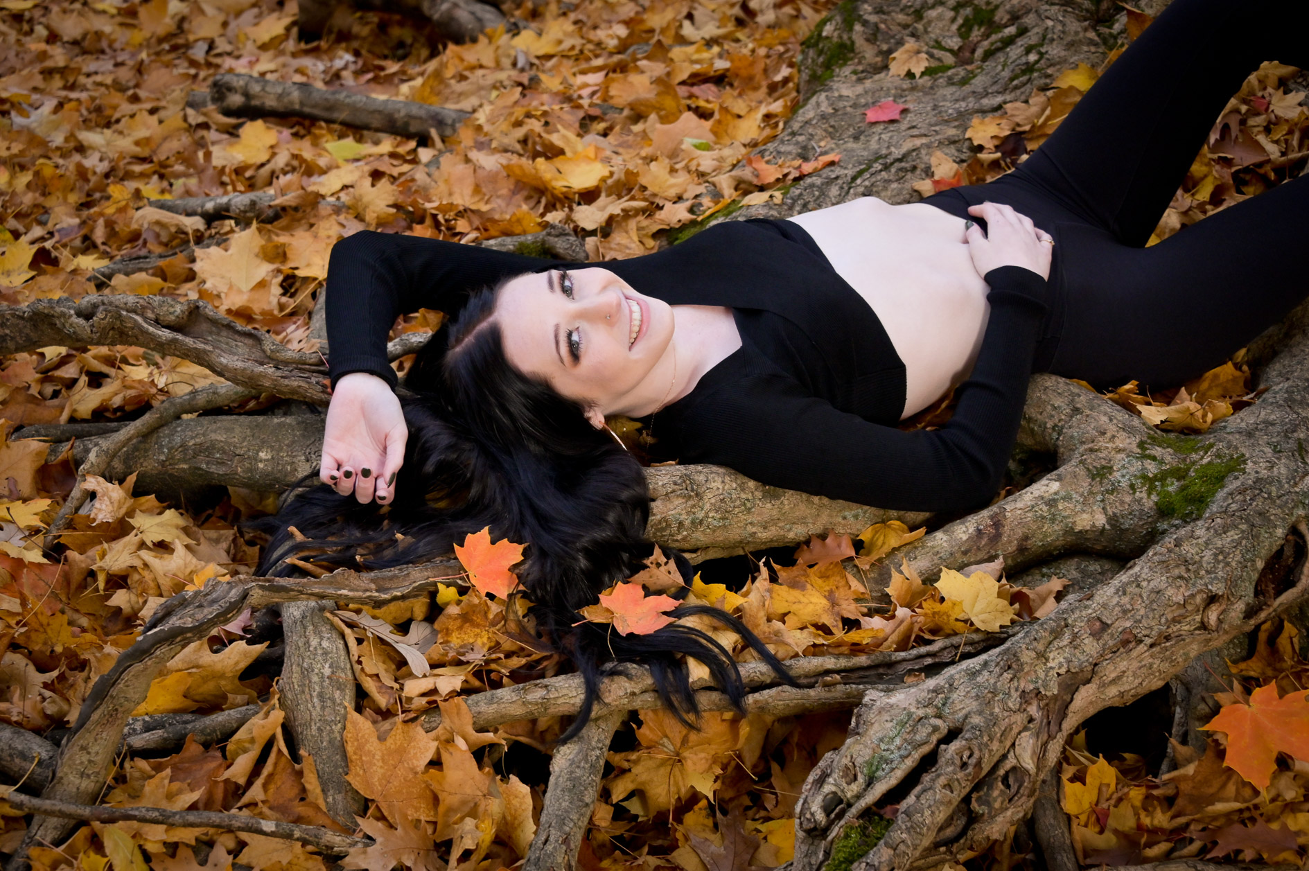 Senior girl drapes herself over trees and colorful fall leaves for this gorgeous senior picture near Troy.