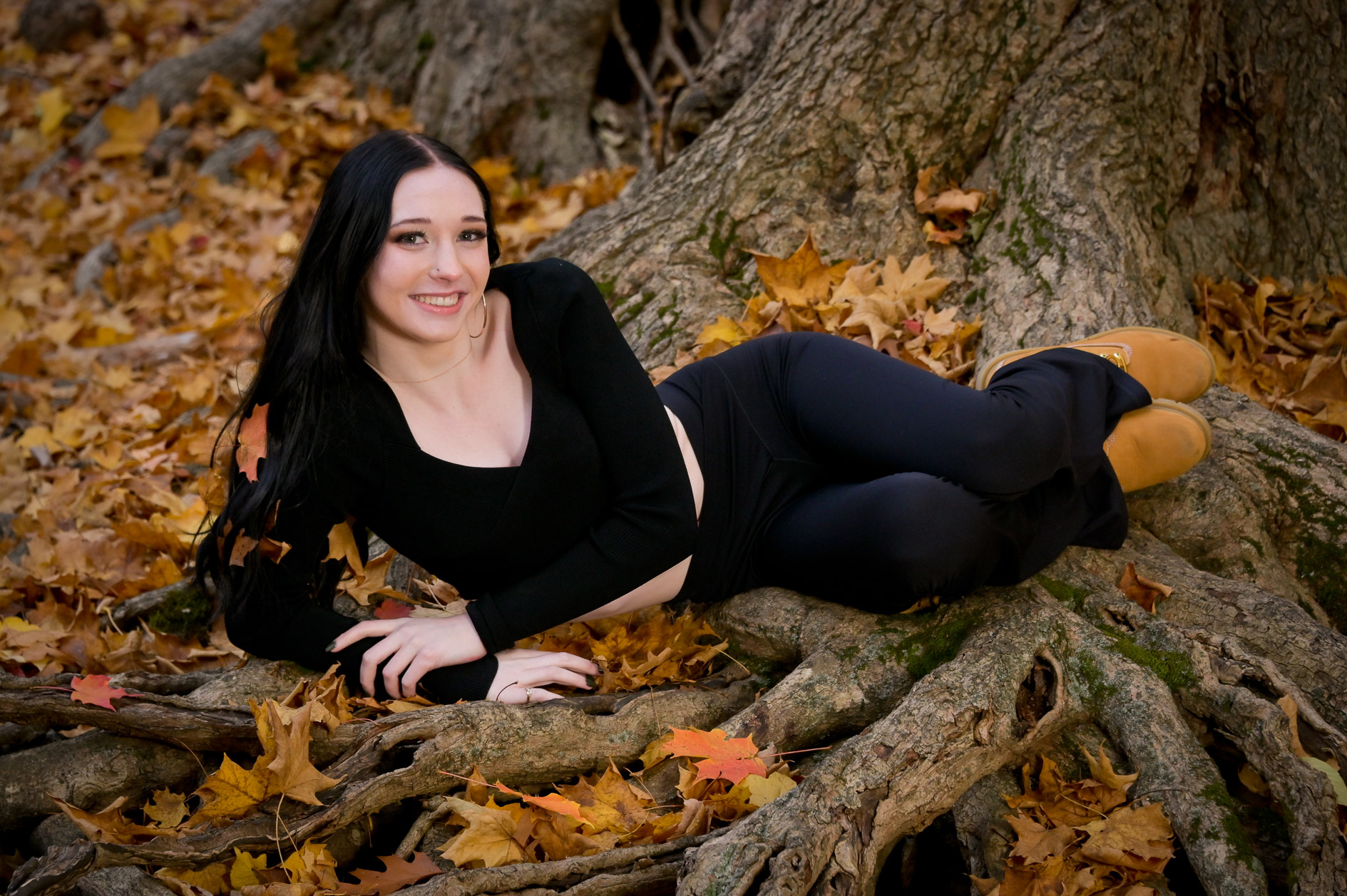Troy, Michigan senior drapes in tree roots with fall leaves in her hair.