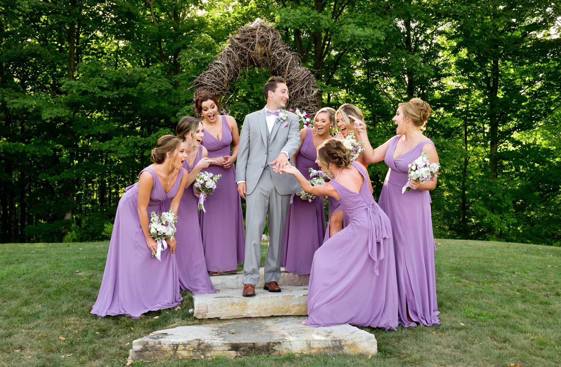 The groom makes fun of all the wedding ring photos while surrounded by the bridesmaids at this destination wedding in Traverse City, Michigan.