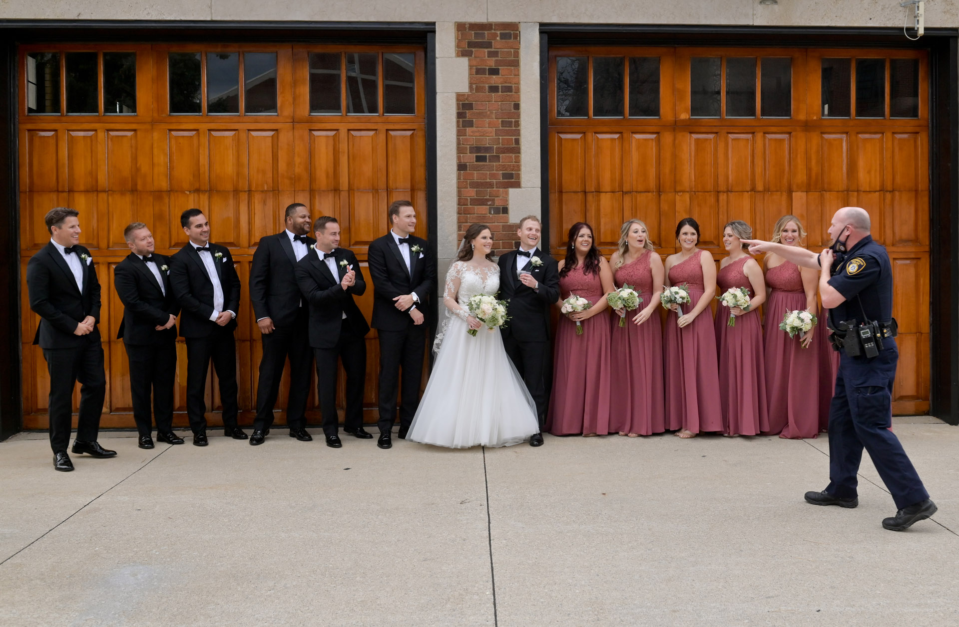 A Birmingham, Michigan police officer comes to ask the wedding party a couple during photos being taken of the wedding party for a personality driven picture.