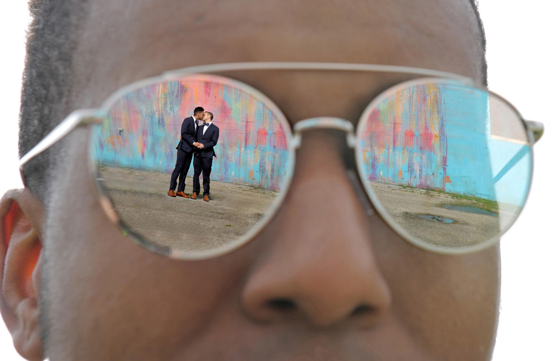 One of the groomsmen reflects two grooms in his sunglasses.