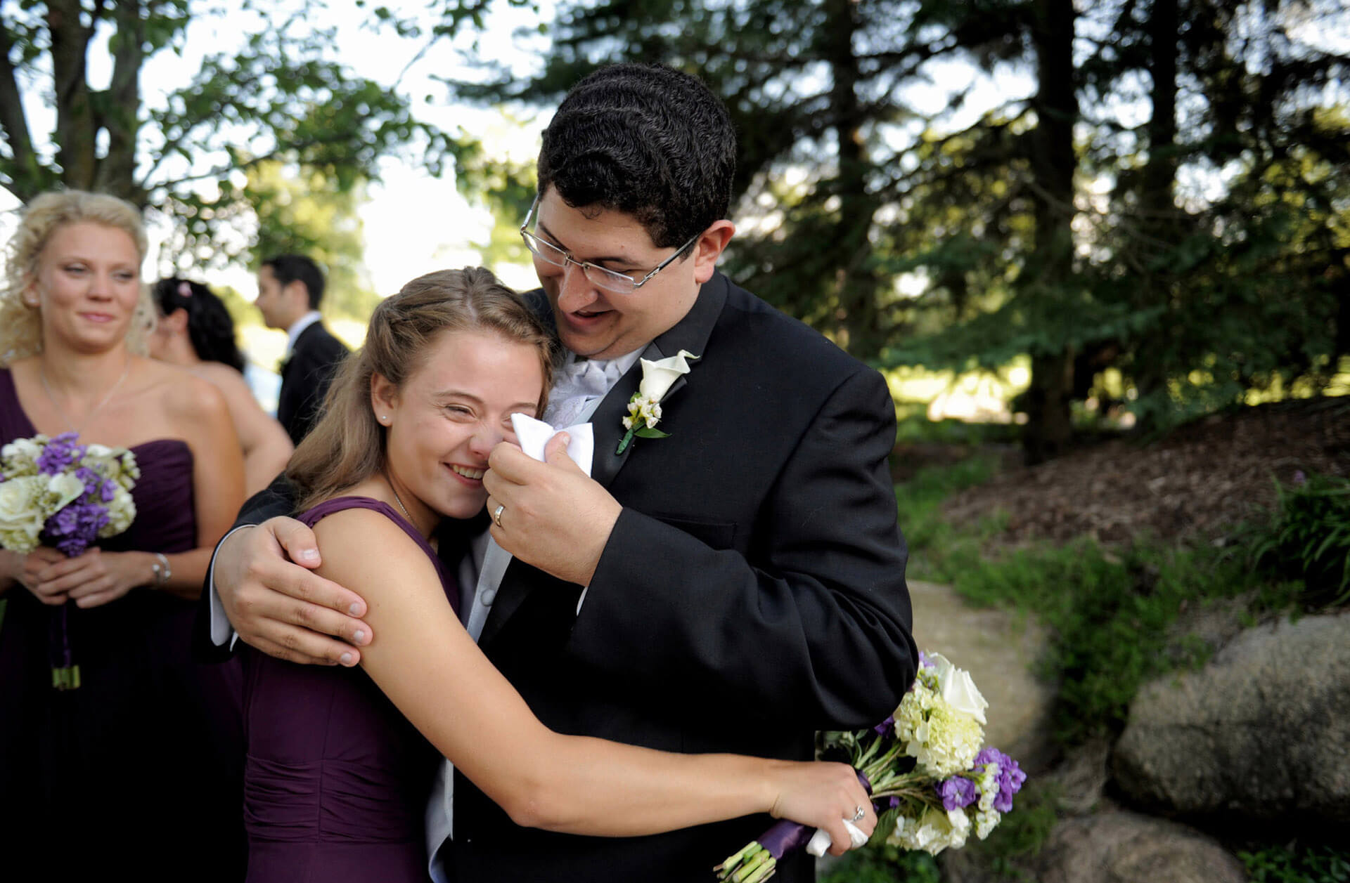 A Rochester, Michigan groom wipes away his new sister in law's tears after his wedding which capitalized on one of Michigan's best wedding photojournalists.