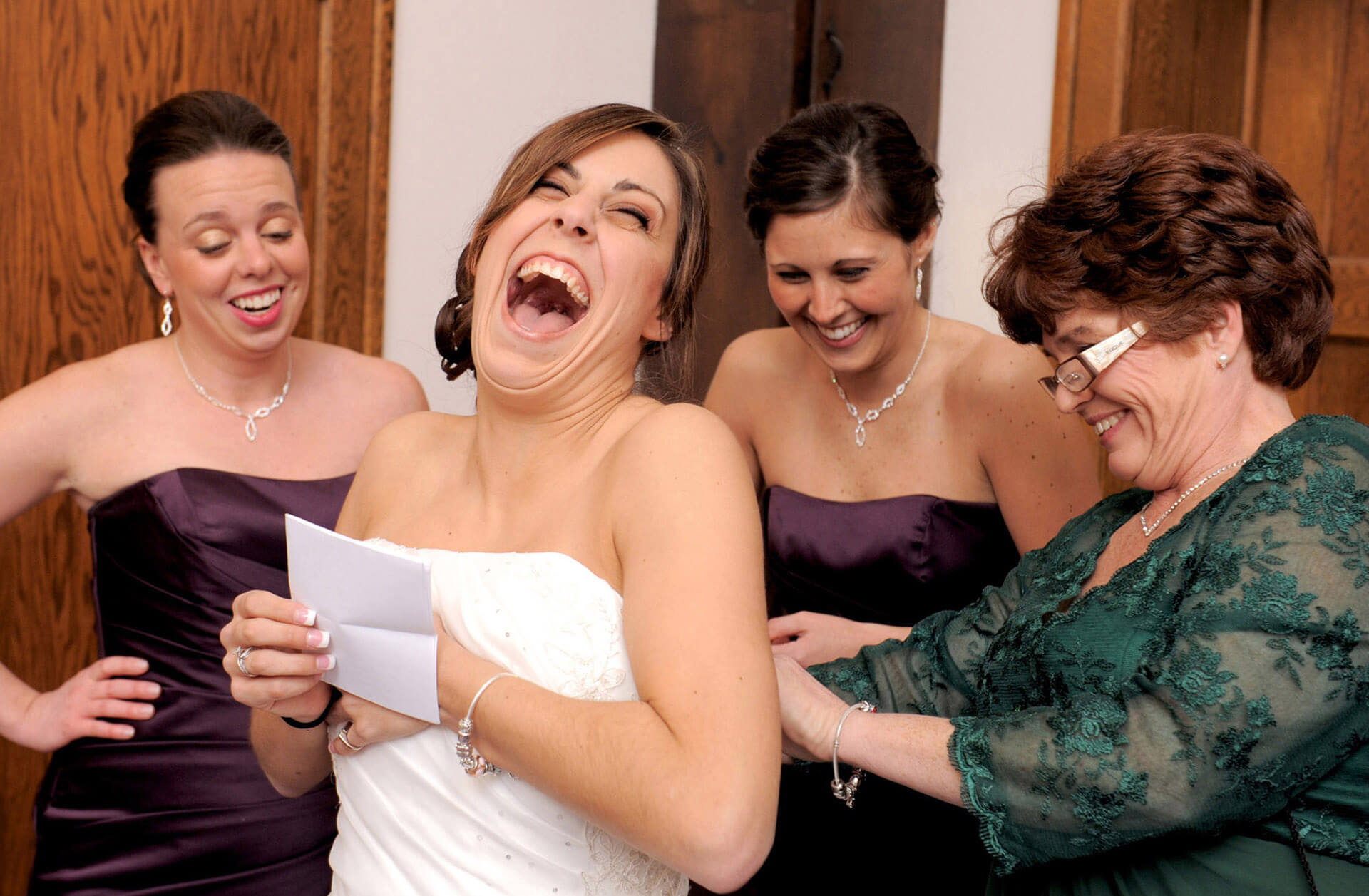 An Ypsilanti, Michigan bride laughs as she tries to read her romantic letter from her husband while being zipped into her dress on her wedding day.