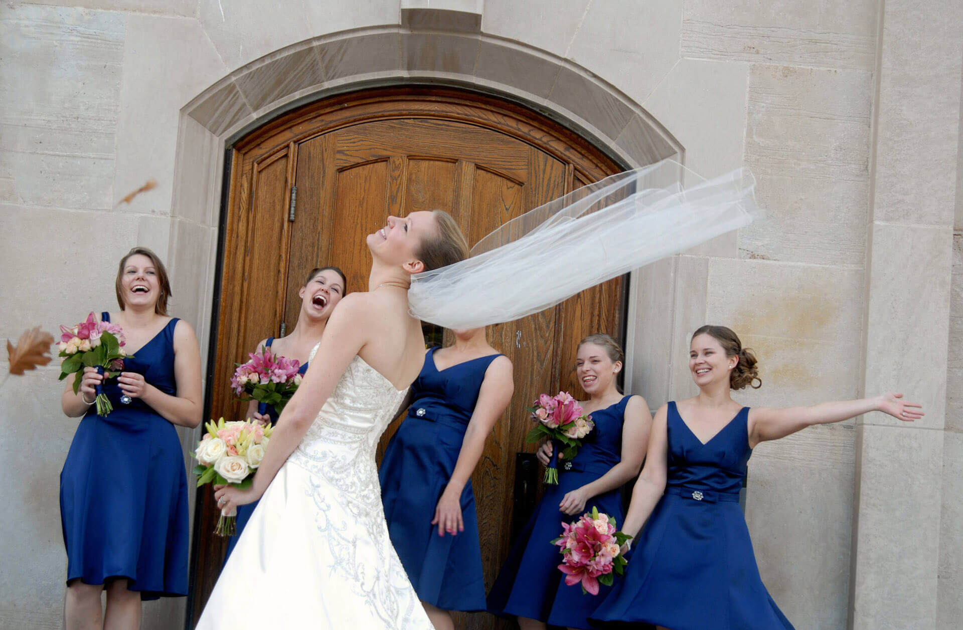 An Ann Arbor, Michigan bride playing in the wind with her bridesmaids.