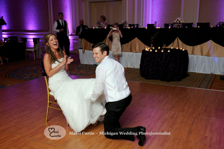 Wedding photography of a Michigan bride and groom taking off the garter in Dearborn, Michigan at their wedding reception at The Henry.