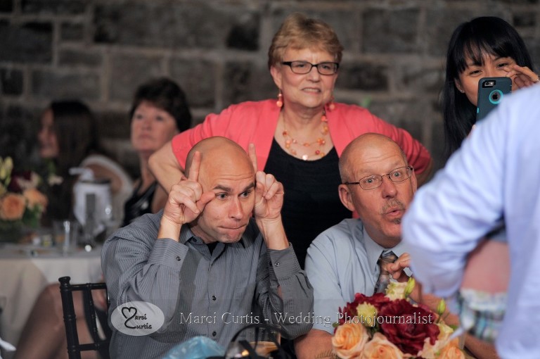 Some of the guests try to elicit a response from a baby they are trying to photograph during a Wellers wedding reception in Saline, Michigan.