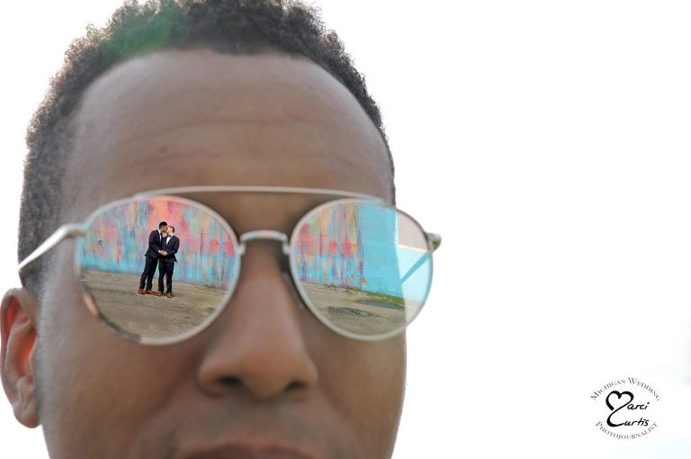 A couple is reflected in their officiant's eyes at Detroit's Bleeding Rainbow wall.