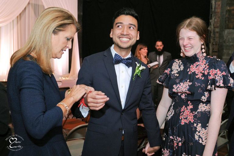 A string is tied onto the groom's wrist after their wedding ceremony at the Jam Handy in Detroit.