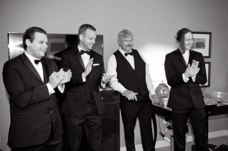 Groomsmen react to the groom reading the note from his bride shortly before his wedding while he's getting ready at the Townsend Hotel in Birmingham, Michigan. Photo by Marci Curtis