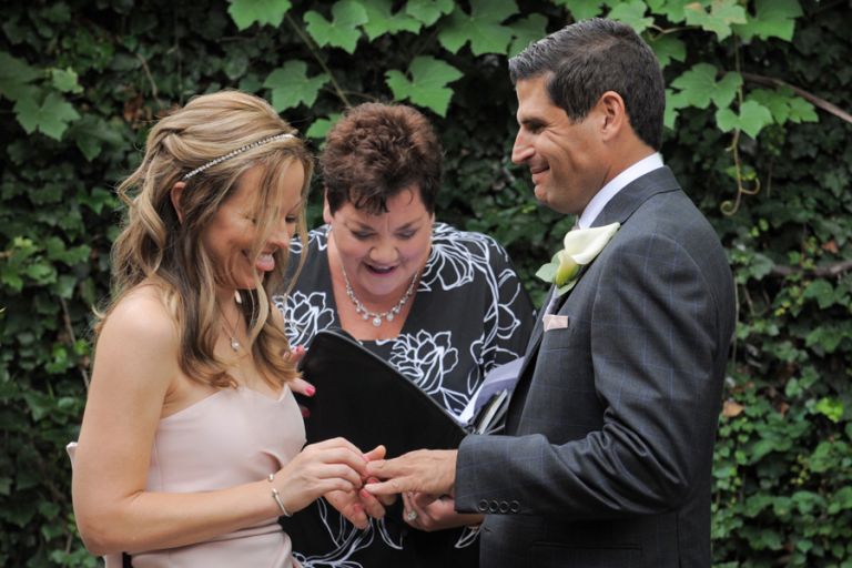 The bride sticks out her tongue putting on the ring during a tiny second wedding at Cafe Cortina in Farmington Hills, Michigan.