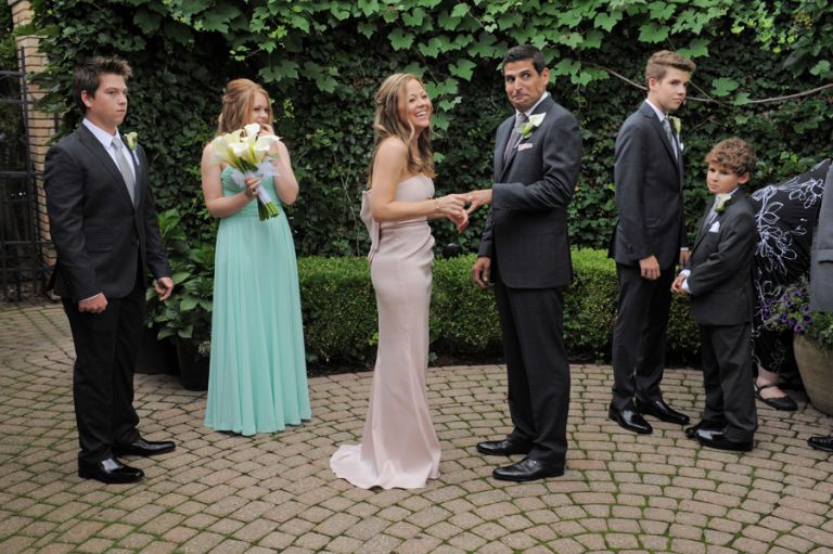 The bride and groom share a funny moment during the ring exchange of a tiny second wedding at Cafe Cortina in Farmington Hills, Michigan.
