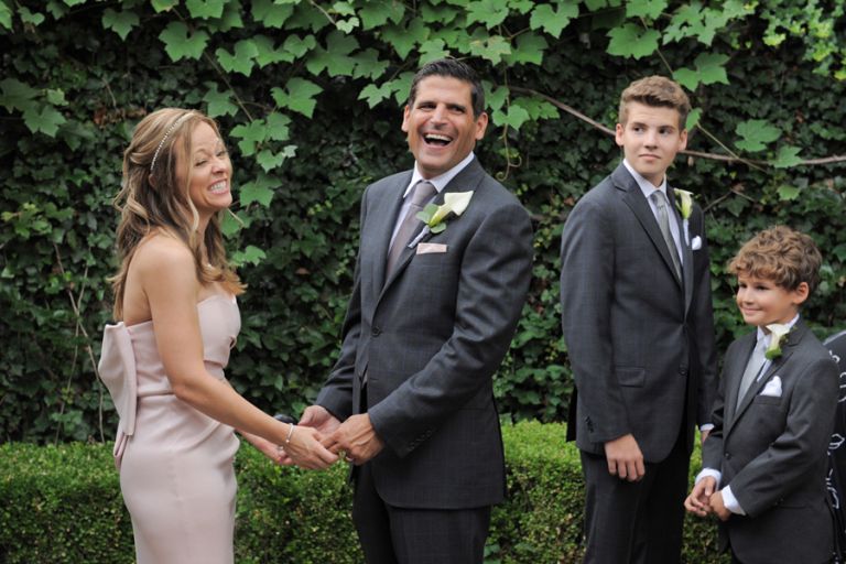 The bride and groom share a funny moment during the ring exchange of a tiny second wedding at Cafe Cortina in Farmington Hills, Michigan.