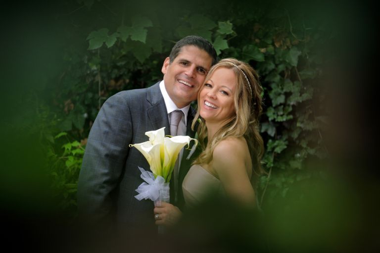 The bride and groom pose through a hole in the wall after their tiny second wedding at Cafe Cortina in Farmington Hills, Michigan.