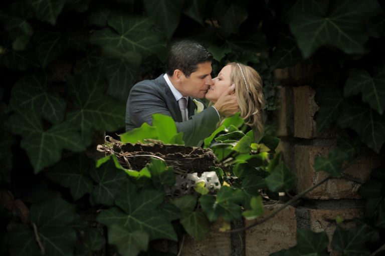 The bride and groom pose through a hole in the wall after their tiny second wedding at Cafe Cortina in Farmington Hills, Michigan.