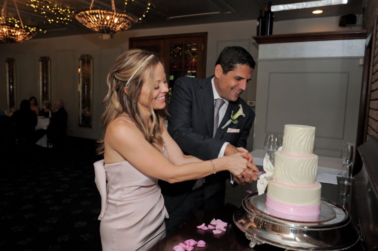The bride and groom fake cutting the cake during the meal after the tiny second wedding at Cafe Cortina in Farmington Hills, Michigan.
